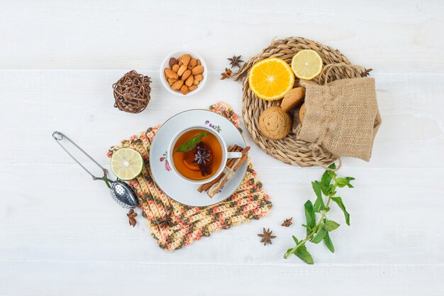 Vista superior de limones y galletas en mantel redondo con una taza de té