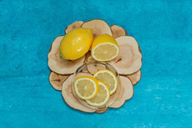 Vista superior de limones y rodajas en rodajas de madera y superficie con textura cian