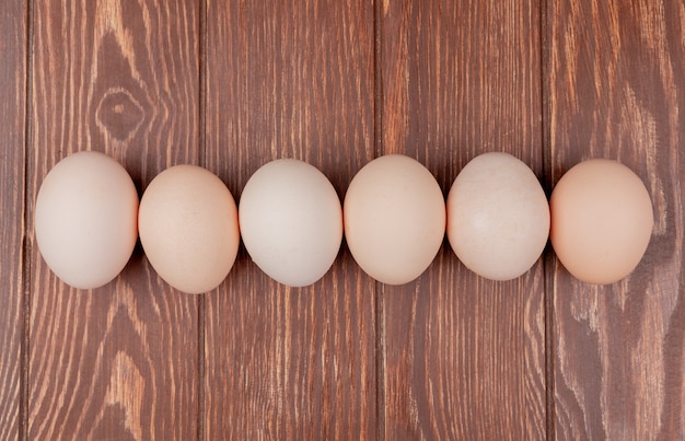 Vista superior de la línea dispuesta de huevos de gallina fresca sobre un fondo de madera