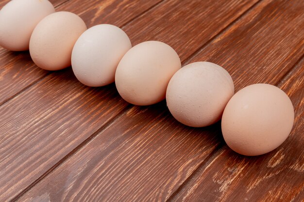 Vista superior de la línea dispuesta de huevos de gallina fresca sobre un fondo de madera