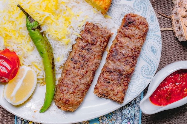 Vista superior de lula kebab con arroz y verduras con una rodaja de limón