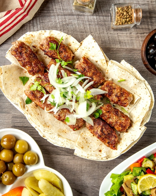 Vista superior de lula kebab en pan de pita con cebolla y hierbas