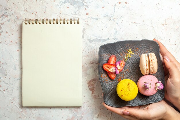 Vista superior de macarons franceses dentro de la placa en la torta dulce de la galleta de la galleta del escritorio blanco
