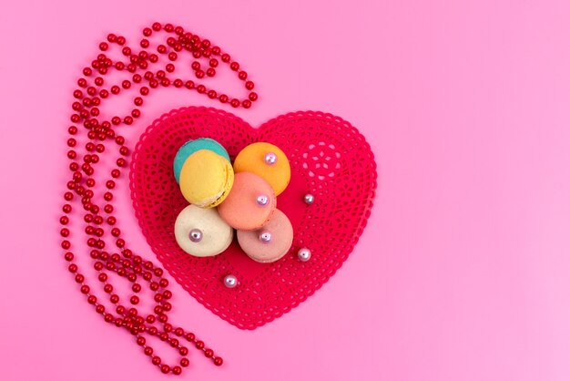 Una vista superior de macarons franceses con forma roja en forma de corazón en rosa, pastelería de galletas y pasteles