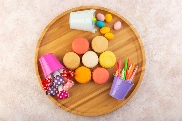 Una vista superior de macarons franceses formados y deliciosos en la mesa rosa pastel galleta azúcar dulce