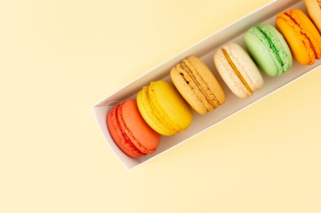 Una vista superior de macarons franceses forrados en la mesa amarilla pastel galleta azúcar dulce