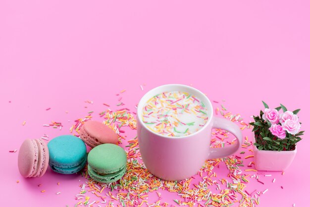 Foto gratuita una vista superior de macarons franceses junto con coloridas partículas de caramelo en rosa, pastel de piso, galleta, azúcar