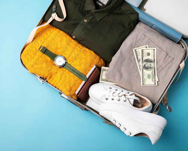 Vista superior de maleta para viajar con ropa y reloj.
