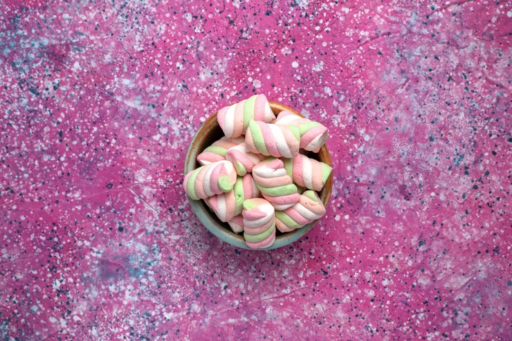 Foto gratuito vista superior de malvaviscos de colores dulces poco formados dentro de una olla redonda sobre la superficie rosa