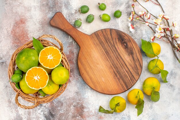 Vista superior de mandarinas frescas en cesta de mimbre una tabla de cortar mandarinas feykhoas sobre fondo desnudo