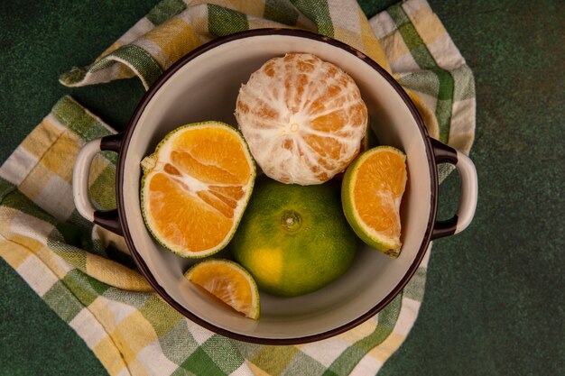 Vista superior de mandarinas frescas y saludables en un recipiente sobre un paño de cuadros