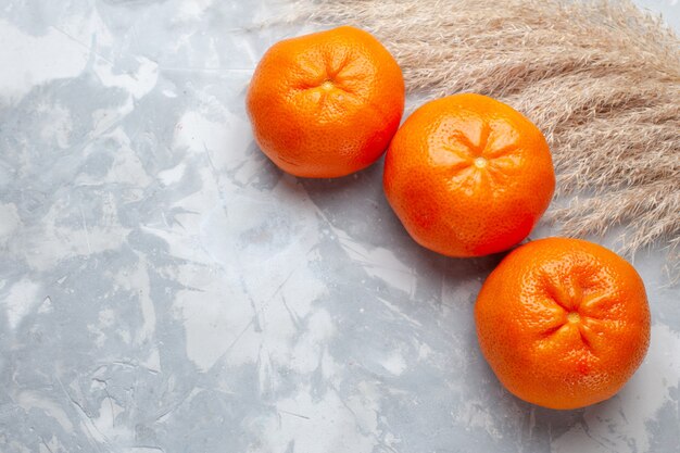 Vista superior de mandarinas naranjas frescas todo jugoso suave sobre el escritorio blanco cítricos vitamina de color exótico