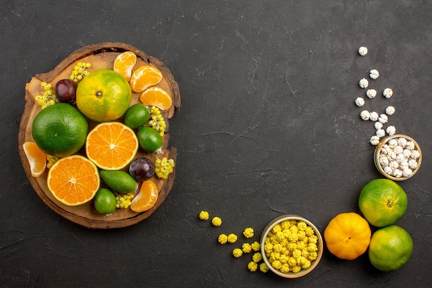 Vista superior de mandarinas verdes frescas con feijoas y dulces en la oscuridad