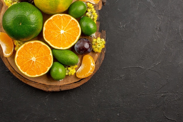 Vista superior de mandarinas verdes frescas con feijoas en la oscuridad