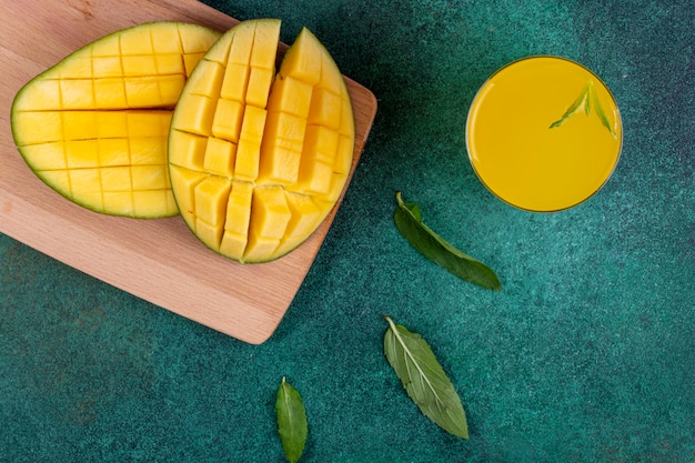 Vista superior de mango en rodajas en la pizarra con un vaso de jugo de naranja