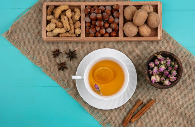 Vista superior de maní con avellanas nueces y una taza de té con canela sobre un fondo azul claro