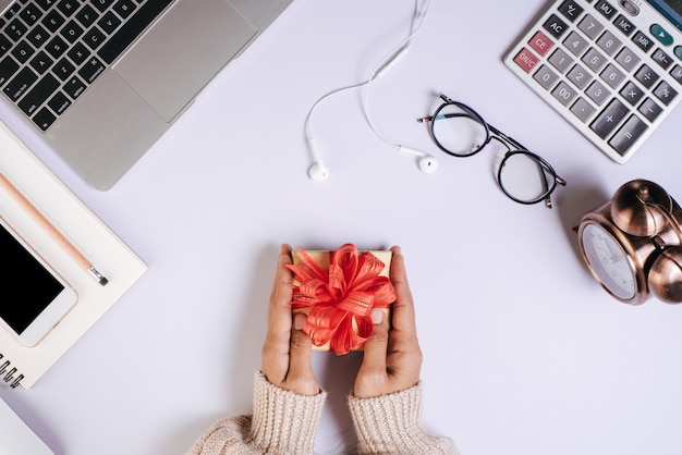 Vista superior de la mano con caja de regalo en el espacio de trabajo