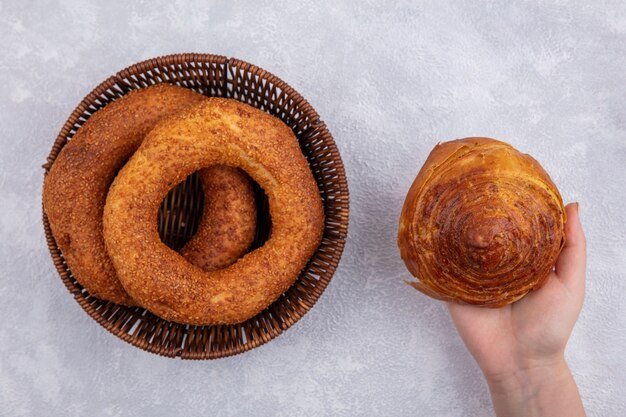 Vista superior de la mano femenina que sostiene el gogal de pastelería azerbaiyano nacional con un cubo de bagels turcos sobre un fondo blanco.