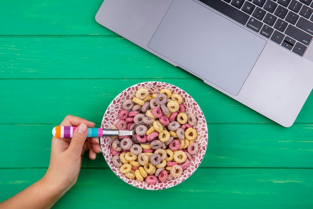 Foto gratuita vista superior de la mano femenina sosteniendo una cuchara llena de cereales de colores en verde