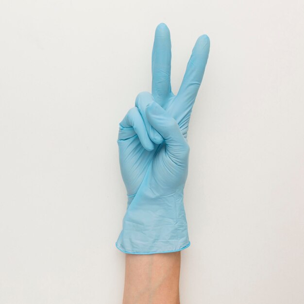 Vista superior de la mano con guantes haciendo el signo de paz