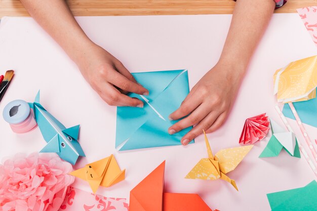 Vista superior de la mano de la mujer que hace el arte del origami sobre la tabla