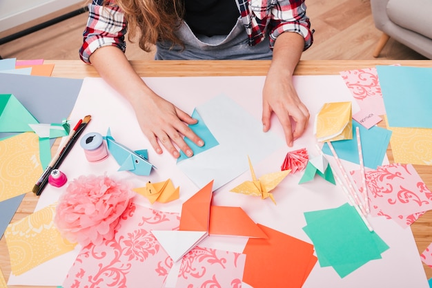 Vista superior de la mano de la mujer que prepara el arte del origami en la mesa
