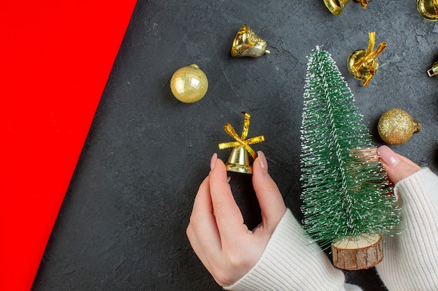 Foto gratuita vista superior de la mano que sostiene un árbol de navidad y accesorios de decoración en la mesa oscura
