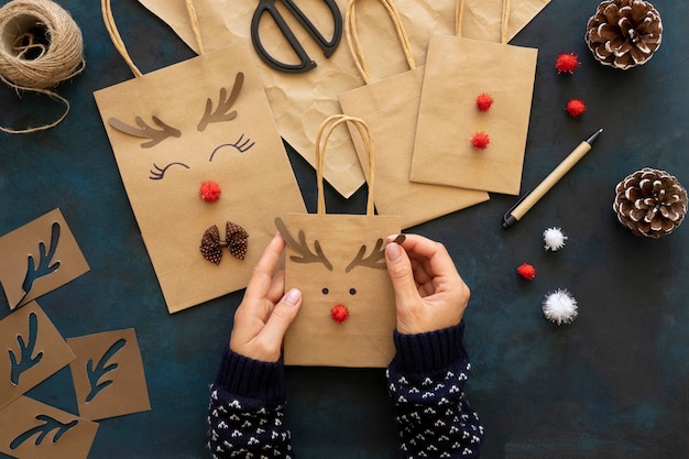 Vista superior de manos decorando bolsas de papel navideñas