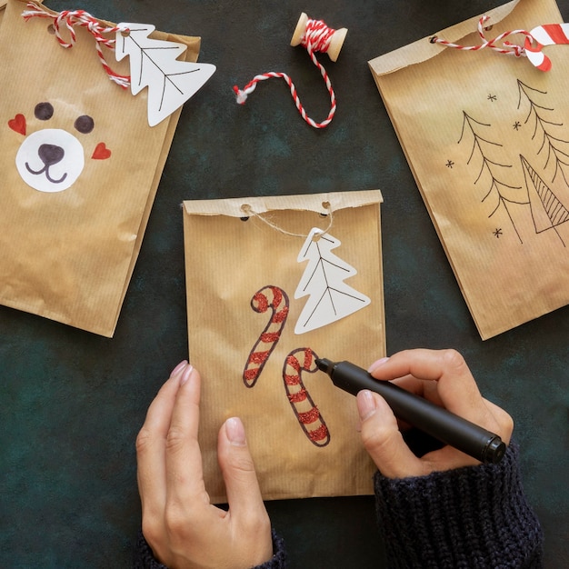 Vista superior de manos decorando bolsas de regalo de navidad