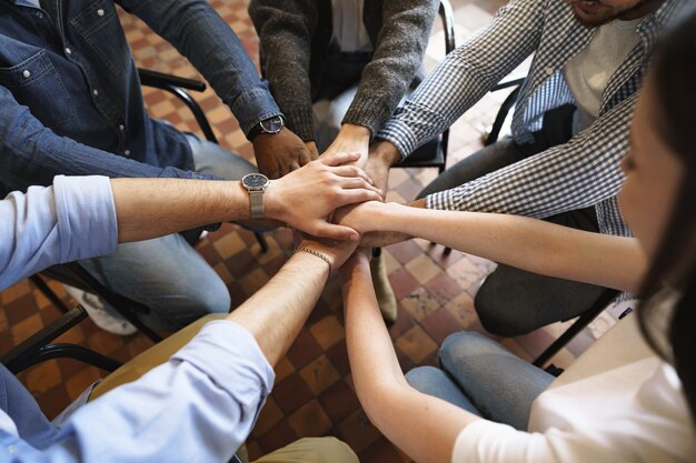 Vista superior de las manos de diversas personas que se unen en la pila de manos de círculo