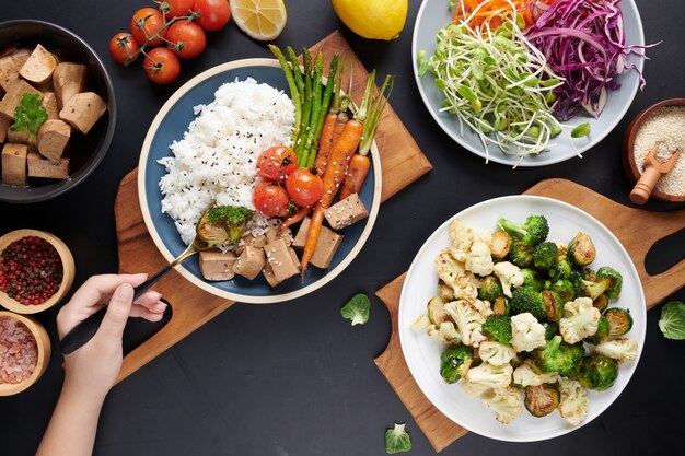 Vista superior de las manos femeninas que sostienen el tazón con ensalada de verduras mixtas, mujer joven comiendo ensalada fresca comida vegetariana.