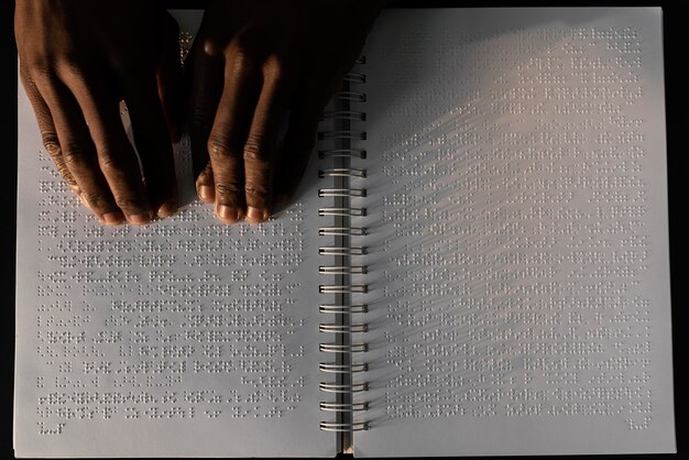 Vista superior manos leyendo cuaderno braille