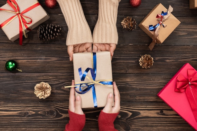 Vista superior de manos masculinas y femeninas sosteniendo caja de regalo roja sobre fondo rosa plano laical. presente para cumpleaños, día de san valentín, navidad, año nuevo. felicitaciones espacio de copia de fondo.