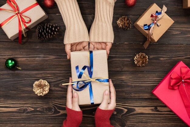 Vista superior de manos masculinas y femeninas sosteniendo caja de regalo roja sobre fondo rosa plano laical. presente para cumpleaños, día de san valentín, navidad, año nuevo. felicitaciones espacio de copia de fondo.