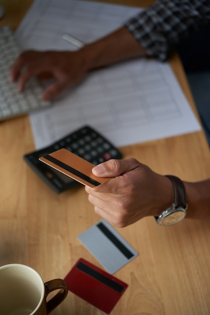 Foto gratuita vista superior de manos masculinas recortadas pagando con tarjeta de plástico para compra en línea