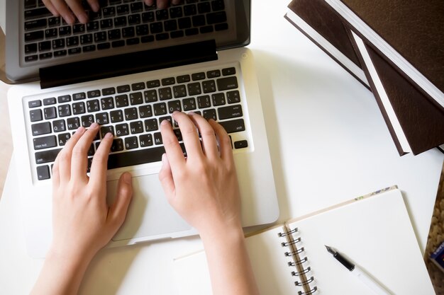 Vista superior de las manos de la mujer que trabaja con la computadora portátil.