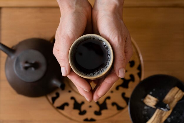 Vista superior de las manos de la mujer con taza de té y hervidor de agua