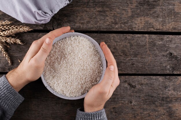 Vista superior manos sosteniendo un tazón con arroz