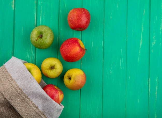 Foto gratuita vista superior de manzanas de colores en una bolsa de arpillera sobre una superficie verde