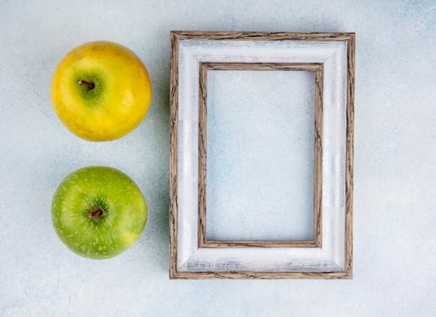 Foto gratuita vista superior de manzanas frescas y coloridas con marco de fotos vacío en blanco