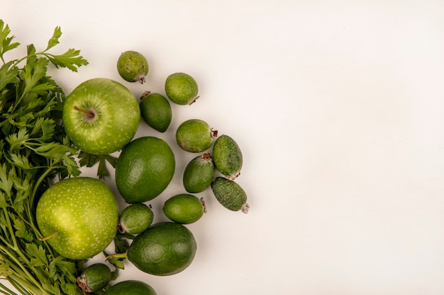 Vista superior de manzanas frescas con limas feijoas y perejil aislado en una pared blanca con espacio de copia