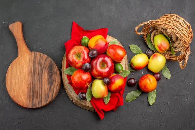 Vista superior de manzanas frescas con melocotones y ciruelas en un jugo maduro de mesa oscura