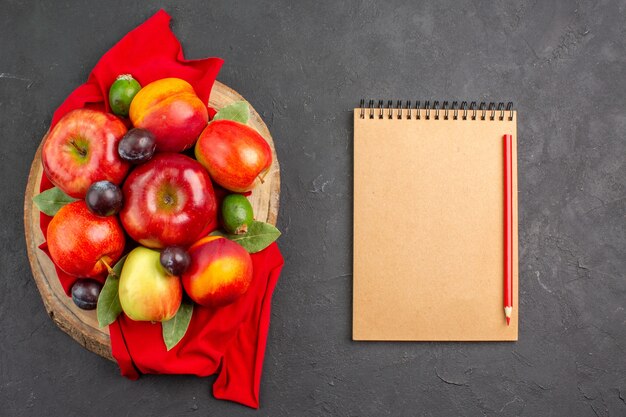 Vista superior de manzanas frescas con melocotones y ciruelas en mesa oscura árbol frutal maduro suave