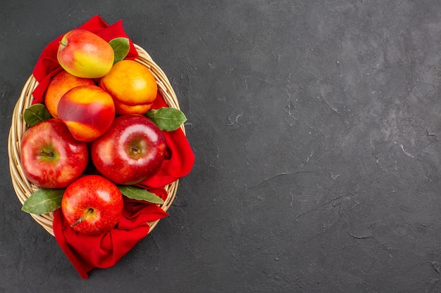 Vista superior de manzanas frescas con melocotones dentro de la canasta en la mesa oscura árbol de fruta fresca madura