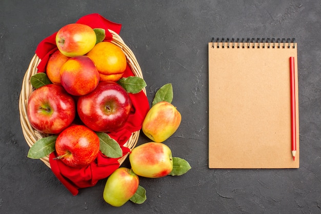 Foto gratuita vista superior de manzanas frescas con melocotones dentro de la canasta en la mesa oscura árbol de frutas maduras frescas