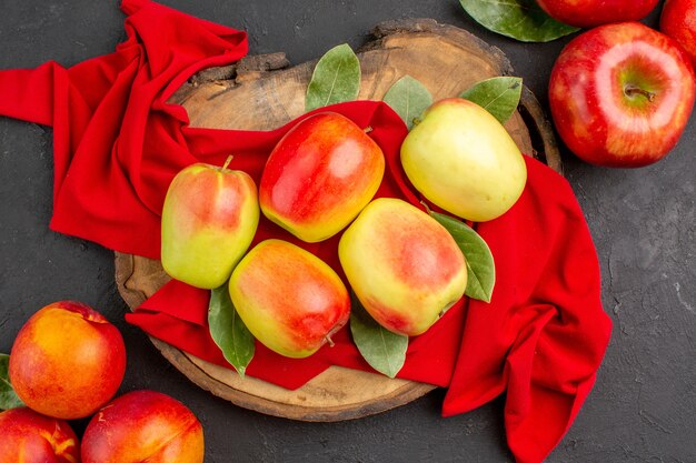 Vista superior de manzanas frescas con melocotones en la mesa de color gris oscuro color de fruta madura fresca