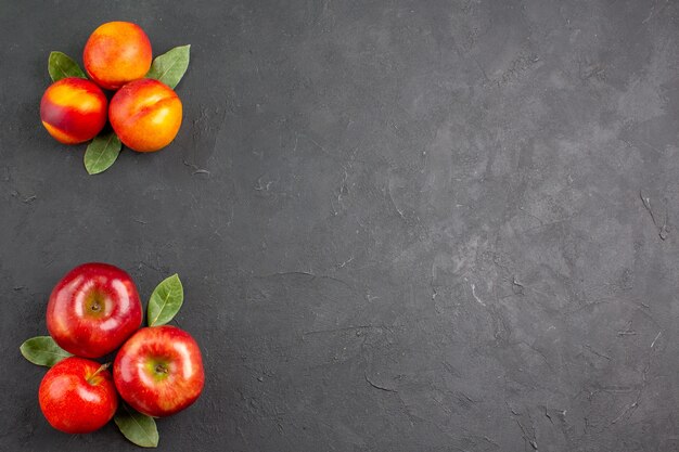 Vista superior de manzanas frescas con melocotones en una mesa oscura frutas maduras frescas de color