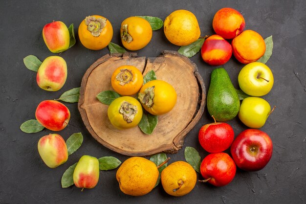 Vista superior de manzanas frescas con peras y caquis en el árbol de la mesa oscura madura fresca suave