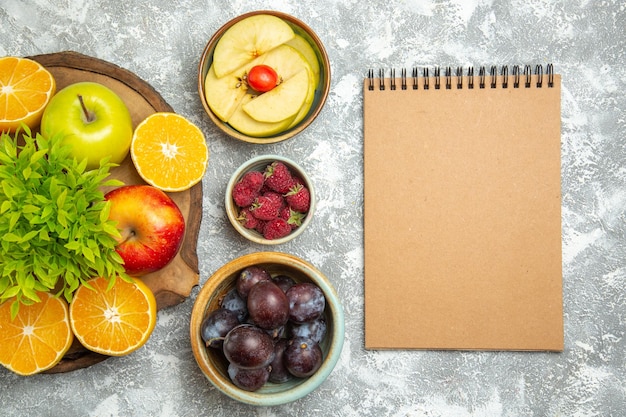 Vista superior de manzanas frescas con rodajas de naranjas y ciruelas sobre fondo blanco frutas maduras suaves manzana fresca