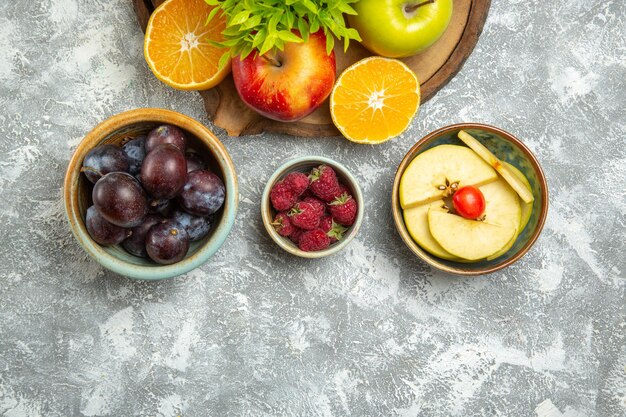 Vista superior de manzanas frescas con rodajas de naranjas y ciruelas sobre fondo blanco manzana madura suave fruta fresca